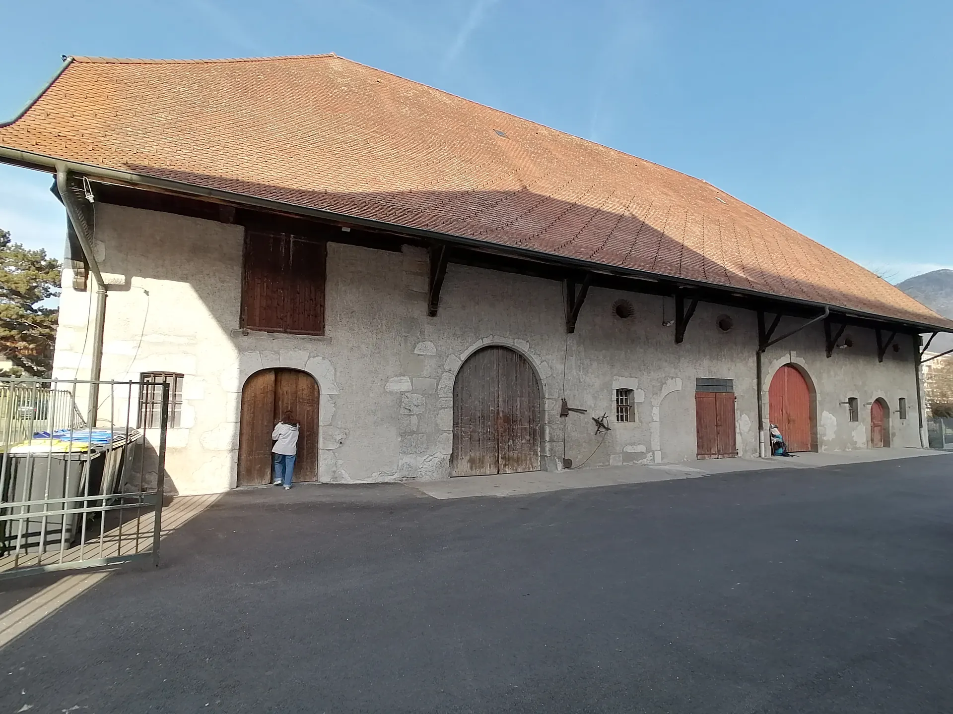 La ferme de Novel aujourd'hui&nbsp;: un long corps de ferme en pierre sous un grand toit de tuiles, percé de portes de bois en arc dont une rouge
